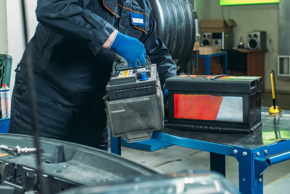 Мастер снимает аккумулятор автомобиля Мастер снимает аккумулятор автомобиля